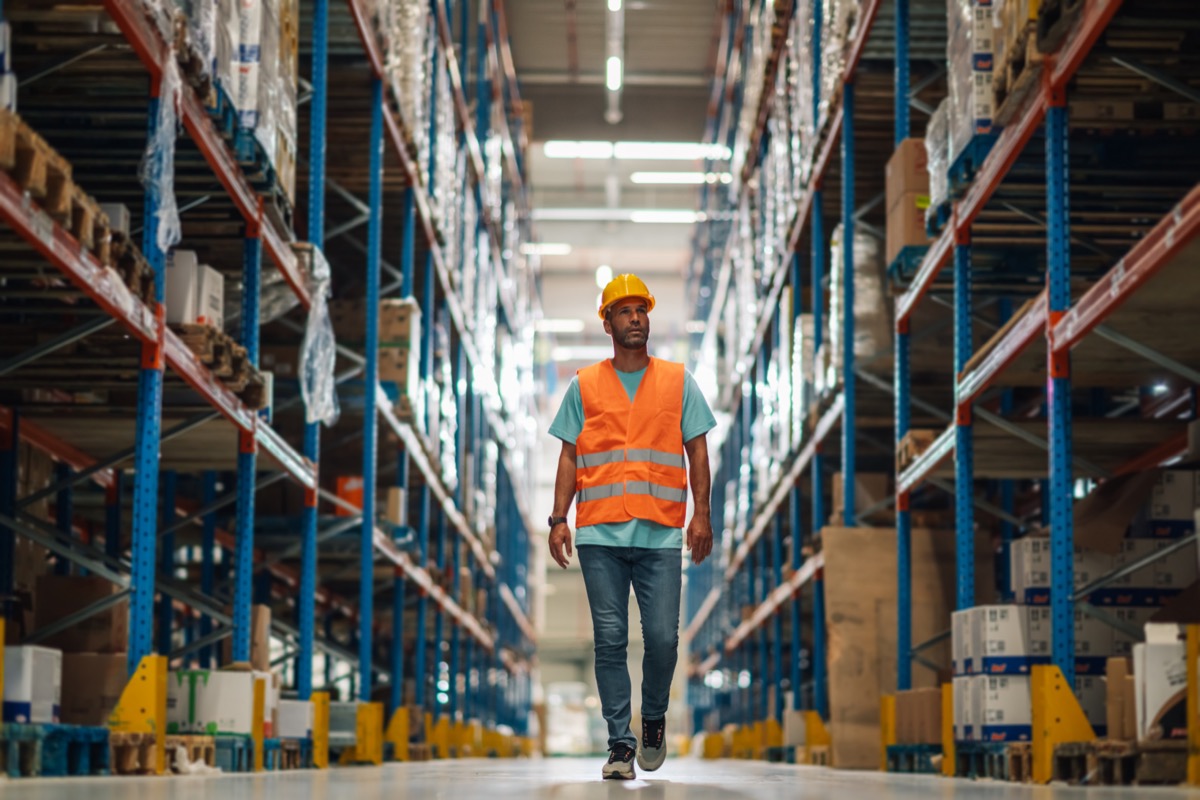 Warehouse worker walking through distribution center aisle